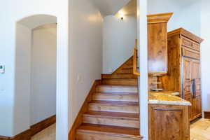 Staircase featuring baseboards and arched walkways