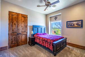 Bedroom featuring a textured wall, carpet floors, and ceiling fan