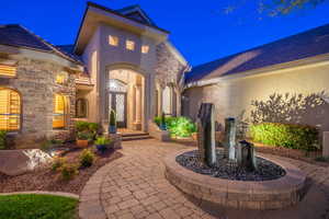 Exterior entry at twilight featuring stone siding and stucco siding