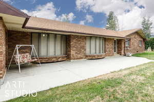 Front of property featuring a shingled roof, brick siding, and a yard