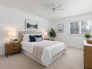 This bedroom is virtually staged. Bedroom with light carpet and a ceiling fan