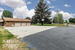 View of side of home featuring an attached oversized 3 car garage, driveway, brick siding, a shingled roof, and a yard