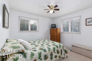 Carpeted bedroom featuring multiple windows and ceiling fan