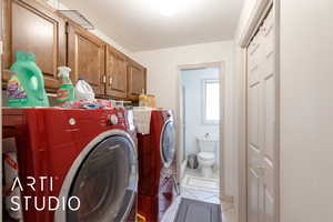 Laundry area featuring light tile patterned floors, a textured ceiling, washer and clothes dryer, and cabinet space