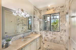 Full bathroom featuring a marble finish shower and vanity
