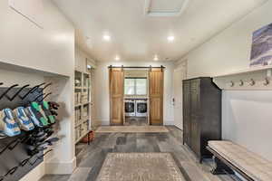 Mudroom with wood tiled floors, a barn door, washing machine and clothes dryer, and recessed lighting