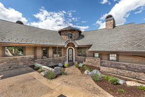 Doorway to property featuring a high end roof, stone siding, and a chimney