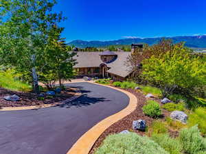 Tudor home featuring a mountain view, stone siding, a chimney, and curved driveway