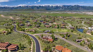 Aerial view of property and surrounding area with nearby suburban area, a water and mountain view, and a golf club
