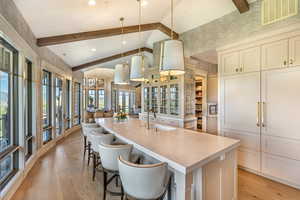 Kitchen with a breakfast bar, decorative light fixtures, a spacious island, lofted ceiling, and light wood-style floors
