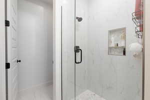 Bathroom featuring a marble finish shower and light marble finish flooring