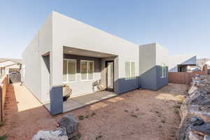 Rear view of house with a fenced backyard, stucco siding, and a patio area