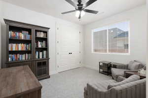 Living area featuring light colored carpet and a ceiling fan
