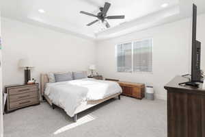 Bedroom featuring light colored carpet, recessed lighting, a raised ceiling, and a ceiling fan