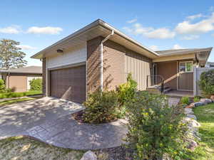 View of front of property with a front yard, brick siding, and concrete driveway