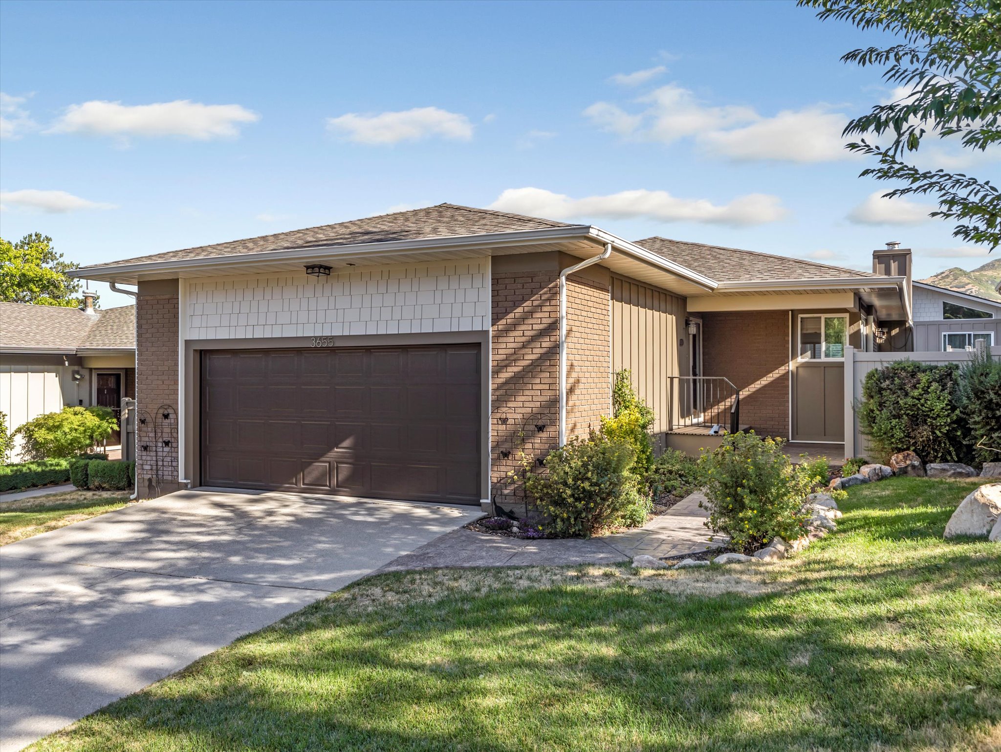Ranch-style house with an attached garage, driveway, roof with shingles, brick siding, and a front lawn