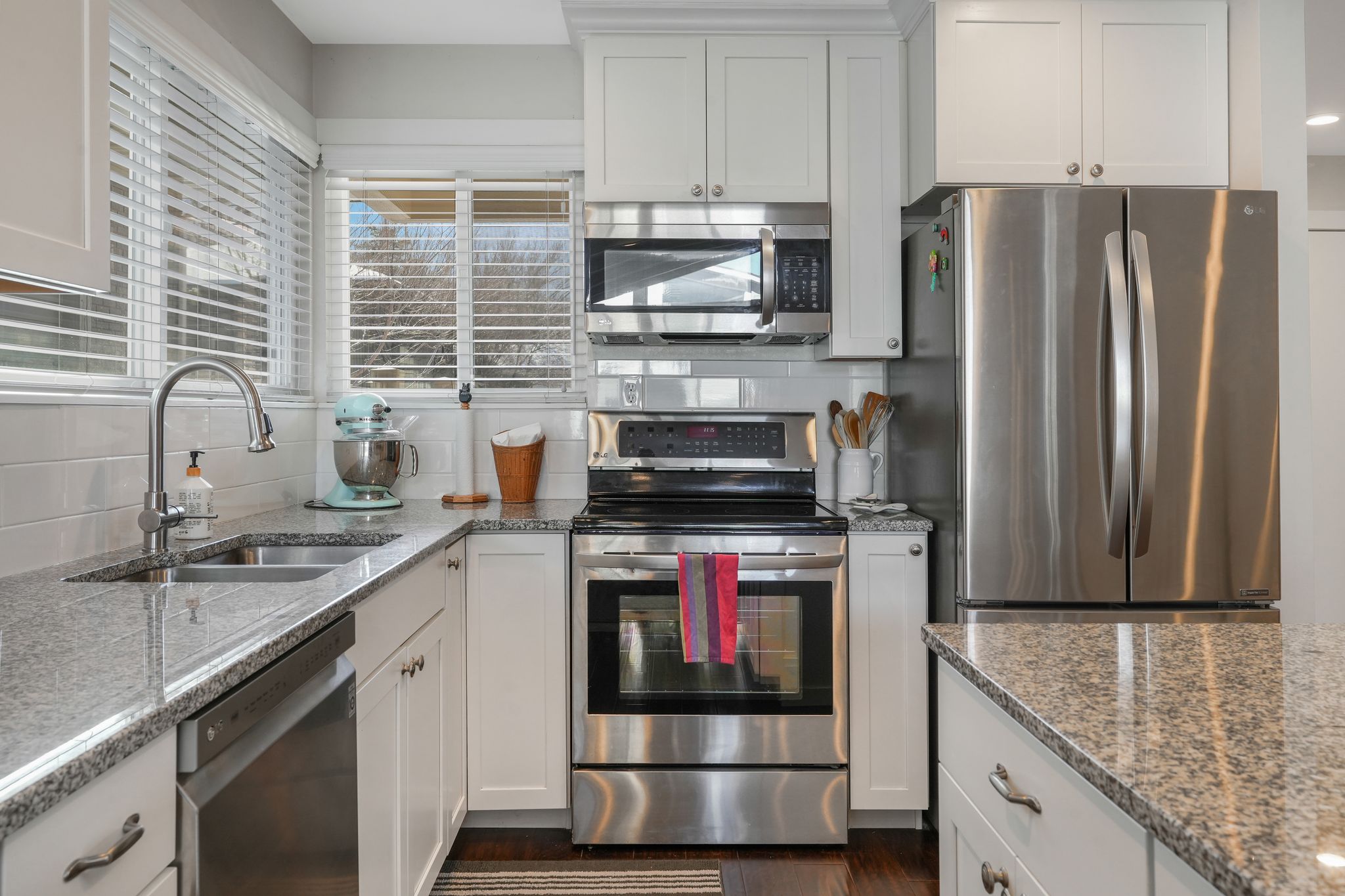 Kitchen with a breakfast bar area, a center island, light stone counters, white cabinets, and dark wood finished floors