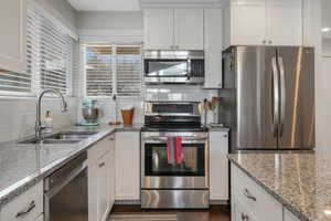 Kitchen with a breakfast bar area, a center island, light stone counters, white cabinets, and dark wood finished floors