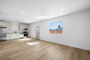 Kitchen with stainless steel appliances, light wood-style flooring, light countertops, recessed lighting, and cream cabinetry