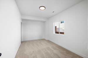 Spare room featuring light carpet and baseboards