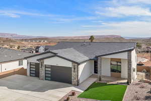 Contemporary home featuring a garage, stucco siding, stone siding, and a mountain view