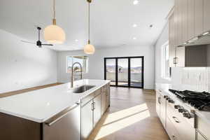 Kitchen with a center island with sink, stainless steel appliances, light wood-style floors, pendant lighting, and open floor plan