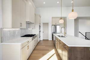 Kitchen with a kitchen island with sink, dual tone cabinets, light wood-style flooring, pendant lighting, and decorative backsplash