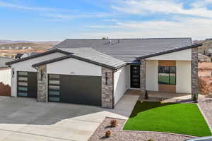 Modern home with a garage, stucco siding, driveway, and stone siding