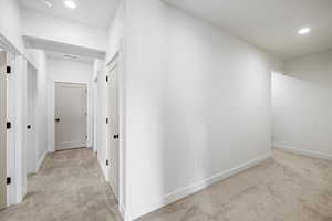 Hallway with light colored carpet and recessed lighting
