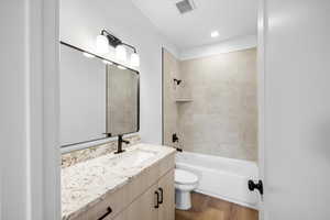 Bathroom with vanity, washtub / shower combination, wood finished floors, and recessed lighting