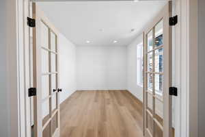 Empty room with french doors, light wood-style floors, and recessed lighting