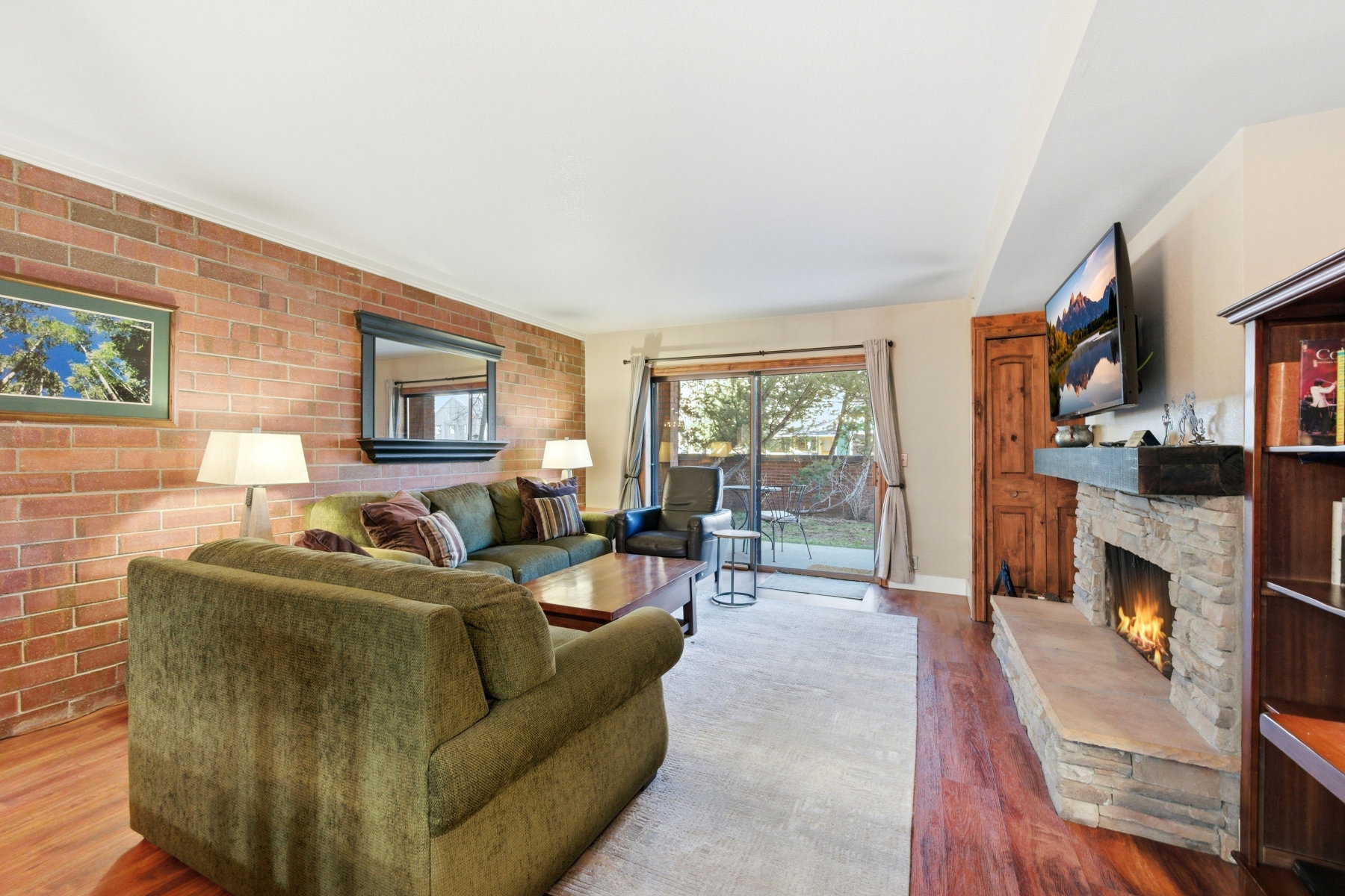 Living area featuring brick wall, a fireplace, and wood finished floors