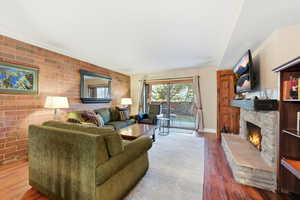 Living area featuring brick wall, a fireplace, and wood finished floors