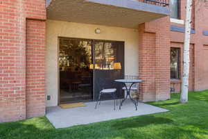 Doorway to property featuring brick siding, a patio area, and stucco siding
