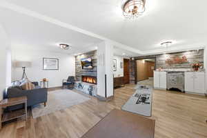 Living room with a fireplace, light wood finished floors, and an accent wall
