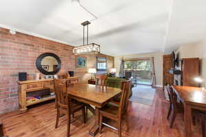 Dining area featuring brick wall and wood finished floors