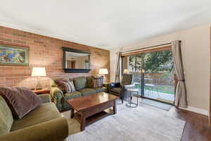 Living area with brick wall, wood finished floors, and an accent wall