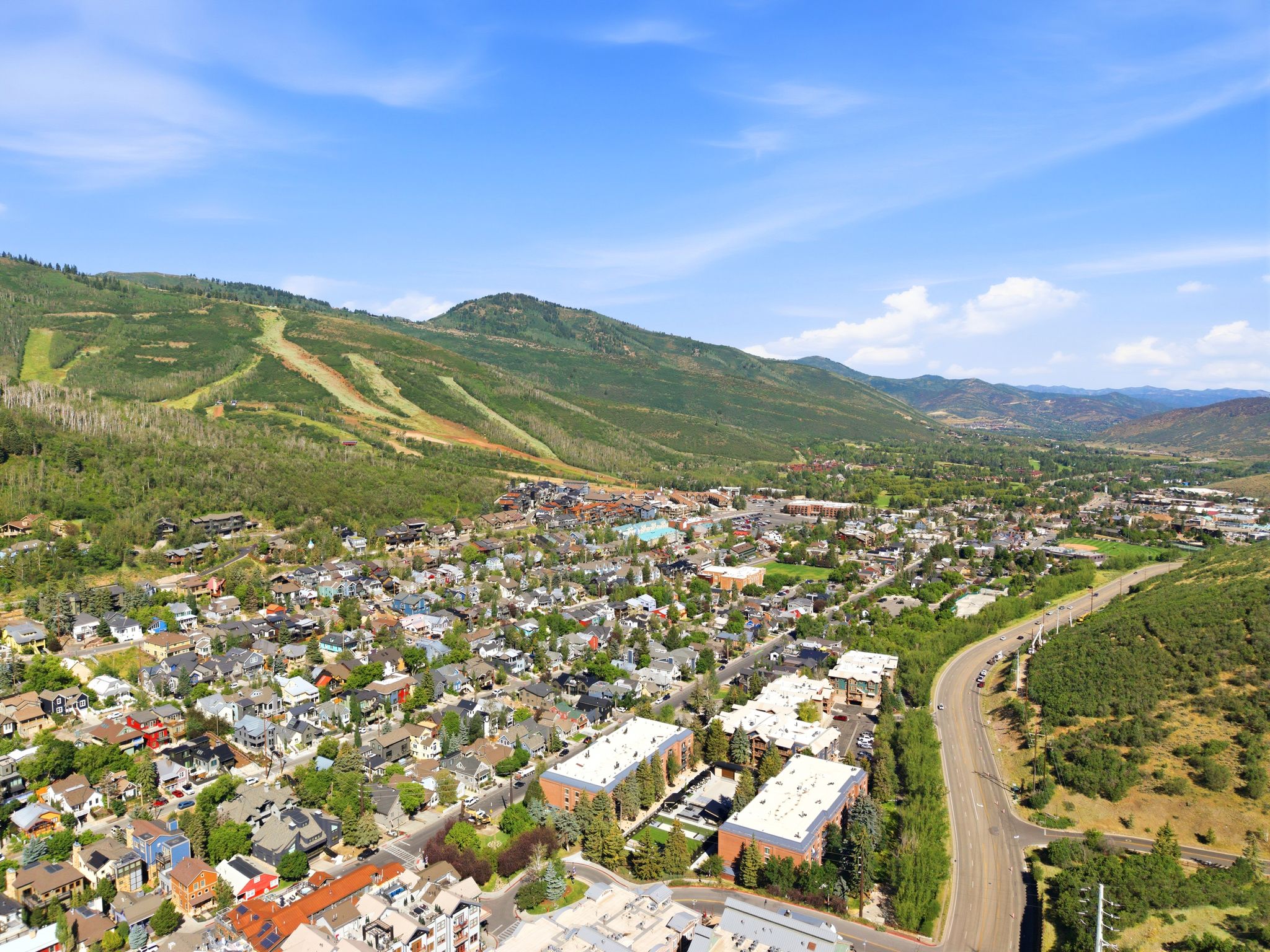 Expansive aerial perspective showcasing a mountainous landscape with a developed community featuring residential properties, commercial buildings, and infrastructure