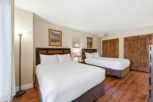 Bedroom featuring multiple closets and dark wood-style flooring