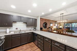 Kitchen featuring dark wood finish cabinets, light wood finished floors, stainless steel appliances, and light stone counters