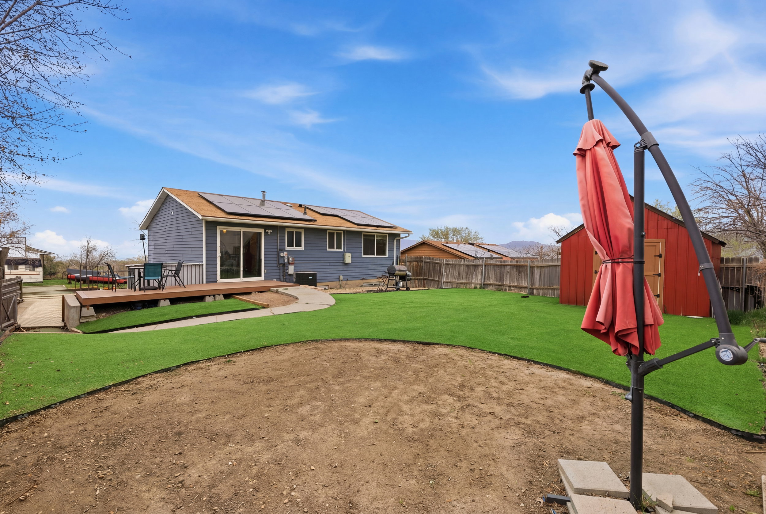 Rear view of property with roof mounted solar panels, a deck, a fenced backyard, and a storage shed