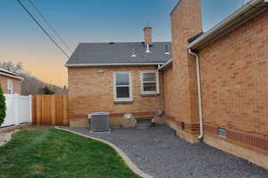 Back of house with brick siding, a chimney, roof with shingles, and crawl space