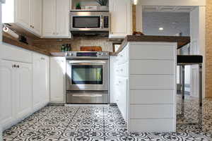 Kitchen with dark countertops, white cabinetry, and stainless steel appliances