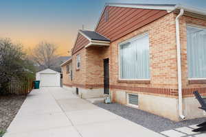 View of side of property with brick siding, a garage, an outbuilding, and driveway