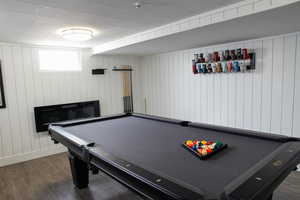 Game room featuring a fireplace, wooden walls, dark wood-style floors, and billiards table