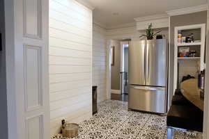 Kitchen with freestanding refrigerator, wooden walls, and crown molding