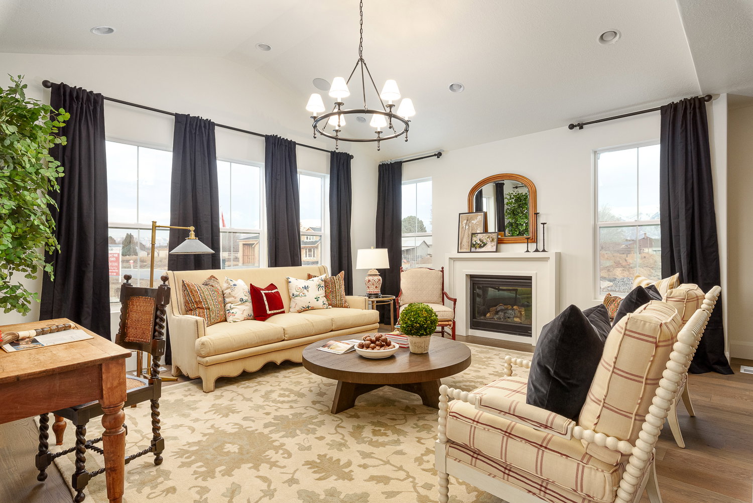 Living room with hanging lights, a glass covered fireplace, wood finished floors, and vaulted ceiling