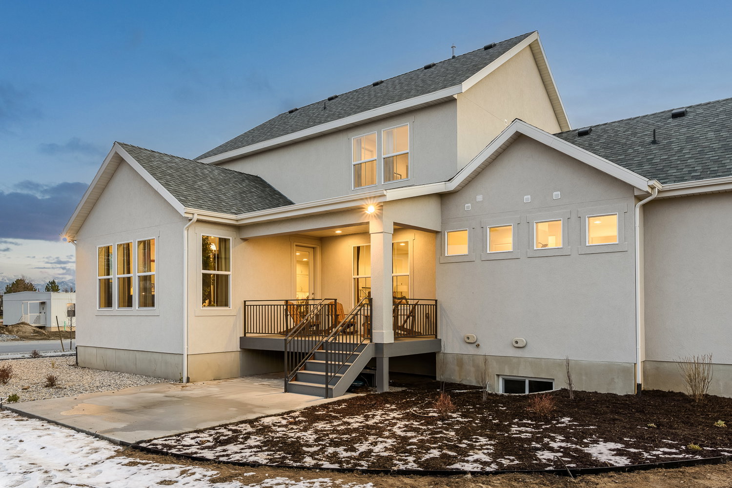 Rear view of house featuring stucco siding, a shingled roof, and a patio area