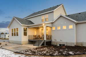 Rear view of house featuring stucco siding, a shingled roof, and a patio area