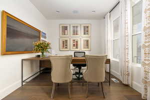 Dining area with dark wood-style flooring and baseboards